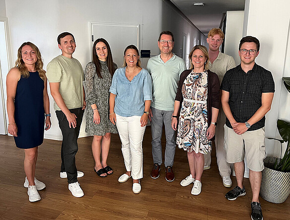 Gruppenfoto mit acht Personen - vier Frauen und vier Männern. Alle lächeln freundlich in die Kamera.