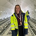 Woman with shoulder-length light brown hair wearing a yellow high-visibility jacket.