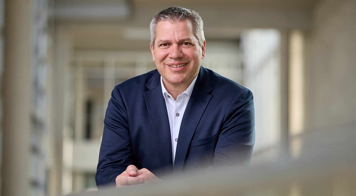 Man with short gray hair, brown eyes, dark blue jacket, and white shirt