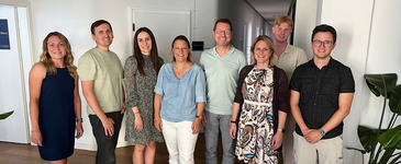 Gruppenfoto mit acht Personen - vier Frauen und vier Männern. Alle lächeln freundlich in die Kamera.