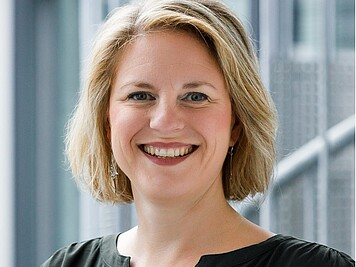 Freundlich lächelnde Frau mit mittellangen blonden Haaren und schwarzer Bluse